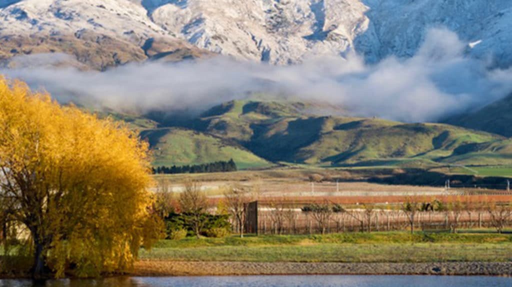 Autumn view across the water towards Kopuwai Delta Vineyard, with low cloud over the hills